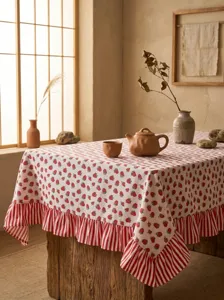 Detail of strawberry print tablecloth with red striped ruffle in rural setting.