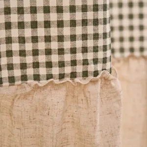 Detailopname van groene gingham-stof en beige linnen textuur met ruches van een gordijn.
