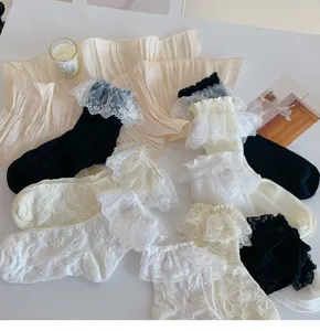 Detail view of sweet Lolita lace ruffle socks flat lay with aesthetic props on clean white desk.