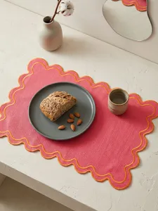 Close-up of embroidered placemat with wavy borders on a table setting
