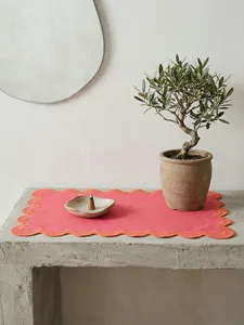 Embroidered pink linen placemat with scalloped edges in a modern home decor setting