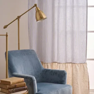 Rideau à rayures bleu et blanc avec volant en lin beige dans un salon confortable