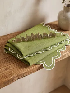Close-up of green imitation linen placemat with white scalloped embroidered edges