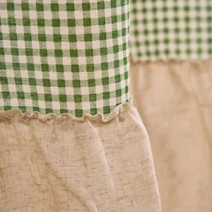 Nahaufnahme von grün-weiß karierten und beige Leinenvorhängen mit Rüschenverzierung