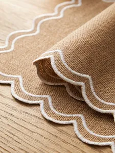 Close-up of retro embroidered placemat with white scalloped edges and jute texture