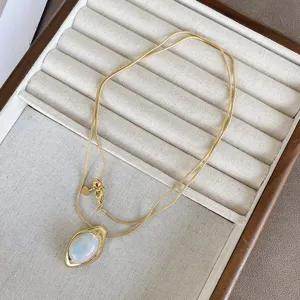Close-up of golden necklace with oval agate stone pendant on jewelry tray