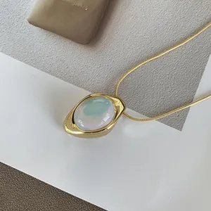 Close-up of vintage gold necklace with iridescent oval opal-like agate pendant.