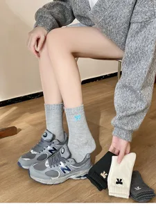 Detalle de calcetines bonitos de algodón gris con lazo bordado azul en la modelo