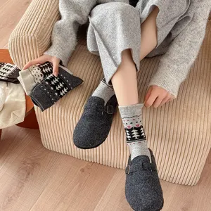 Detailed view of warm Fair Isle tree pattern wool socks paired with grey felt clogs