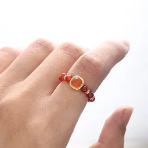 Detailed view of a luxury red agate beaded ring featuring a square center stone on a finger