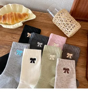 Primer plano de calcetines de algodón con lazos bordados en varios colores sobre una mesa.