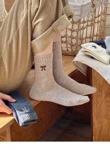 Primer plano de calcetines beige con lazo bordado en un entorno acogedor