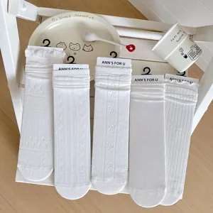 Detalle de cinco calcetines blancos de verano con delicados patrones de encaje calado y lazos