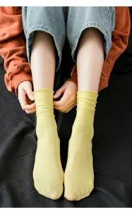 Close-up of vibrant yellow velvet mid-calf slouchy socks worn by a model