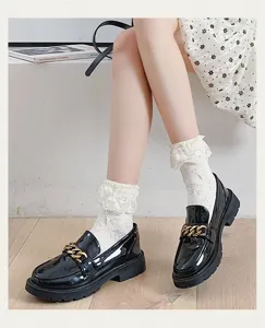 Close-up detail of cute white lace ruffle Lolita socks paired with black chain loafers.