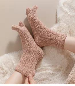 Soft pink coral fleece five-finger socks shown on a white faux fur rug detail view.
