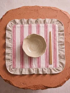 Detail of a red striped linen placemat with elegant ruffled edges for table decor.
