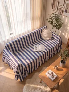 Blue and white striped velvet sofa cover with ruffled edges in a sunlit cozy room