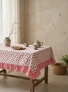 Detail view of pastoral strawberry print tablecloth with red striped ruffle edge