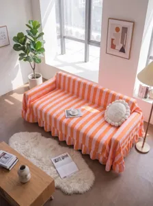 High-weight orange and pink striped flannel sofa throw with ruffled edges in a sunlit room