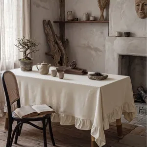 Elegante tovaglia in cotone lavato crema con bordi a balze in un ambiente rustico e accogliente