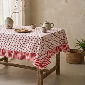 Rustic cotton linen tablecloth with strawberry pattern and ruffled edges on table