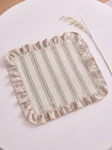Detail view of a striped cotton-linen placemat with elegant ruffled edges on a table.