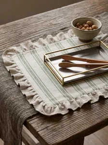 Macro view of ruffled cotton linen placemat with green stripes on rustic wooden table