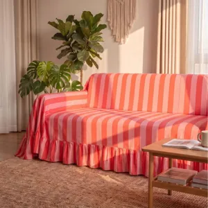 Cozy thick pink and orange striped sofa cover with elegant ruffled edges in sunlight