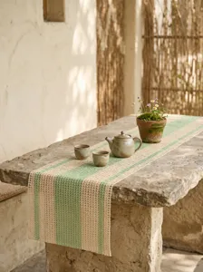 Détail d'un chemin de table tissé rustique à rayures vertes sur une table en pierre