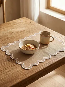 Rustic retro placemat with scalloped edges and white embroidery on a natural wooden table