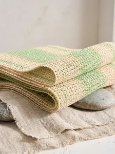 Vue rapprochée du chemin de table en papier tissé rayé vert et beige à texture ajourée
