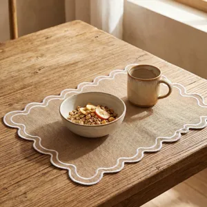 Vintage scalloped edge embroidered placemat with linen-look texture on a wooden table