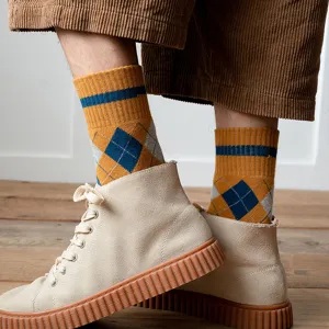 Close-up of men's thick argyle mid-calf socks in ochre yellow with blue diamonds