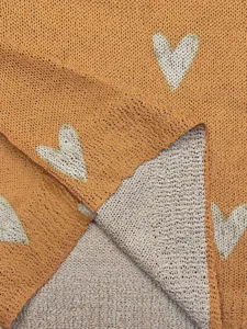 Nahaufnahme eines gelben Vintage-Strickpullovers mit Herzmuster und Jacquard-Gewebe