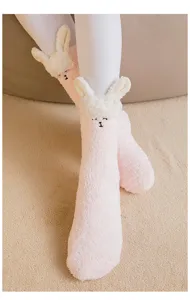Detail of cute pink coral fleece socks featuring a white plush animal character
