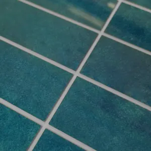 Macro dettaglio della piastrella SPC verde acqua con fughe bianche e trama.