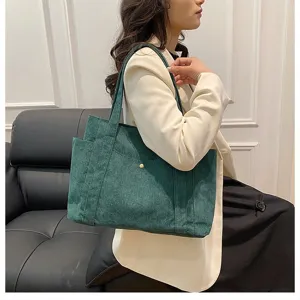 Vista dettagliata di una borsa tote alla moda in velluto a coste verde portata da una modella