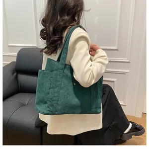 Vista dettagliata di una grande borsa tote in velluto a coste verde scuro indossata