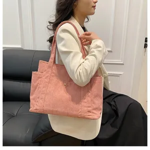 Dettaglio borsa tote in velluto a coste rosa con tracolla e design a tasca laterale