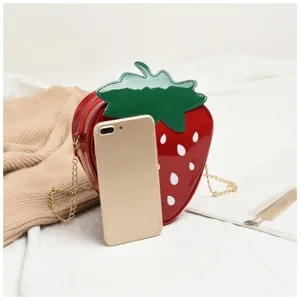 Detailed size comparison of the strawberry-shaped cartoon bag with a gold smartphone