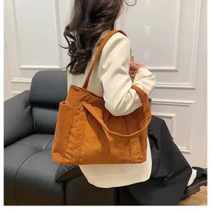 Vista dettagliata di una grande borsa tote in velluto a coste marrone portata a spalla