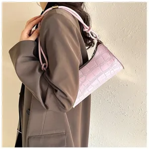 Detailed view of pink crocodile embossed baguette bag worn by a model.
