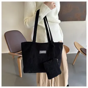 Elegante bolso tote de pana negra con pequeña bolsa a juego llevado por una modelo femenina