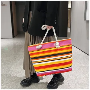 Detailopname van model met een kleurrijke gestreepte canvas tas met touwhandvatten