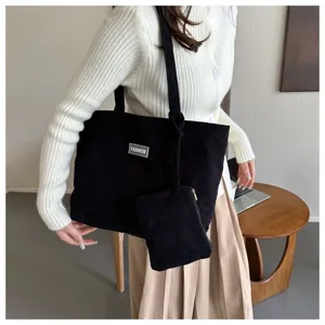 Modelo con bolso tote de pana negra y un pequeño neceser a juego para el uso diario