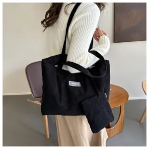 Vista detallada del bolso tote de pana negra con etiqueta de moda y pequeño bolso