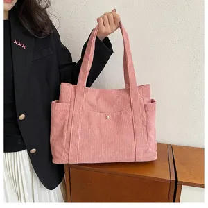 Vista dettagliata di una borsa tote in velluto a coste rosa con finitura e tasche laterali.