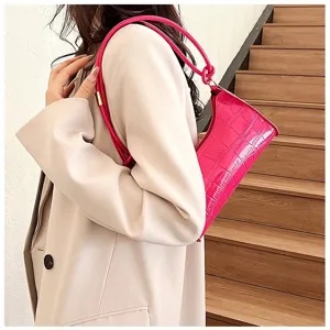 Detail view of a bright pink crocodile pattern underarm bag worn with a beige blazer