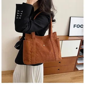 Vista dettagliata di una borsa tote in velluto marrone indossata con un blazer nero chic